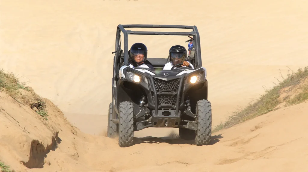 Couple driving a Side by Side UTV through sandy desert trails in Los Cabos