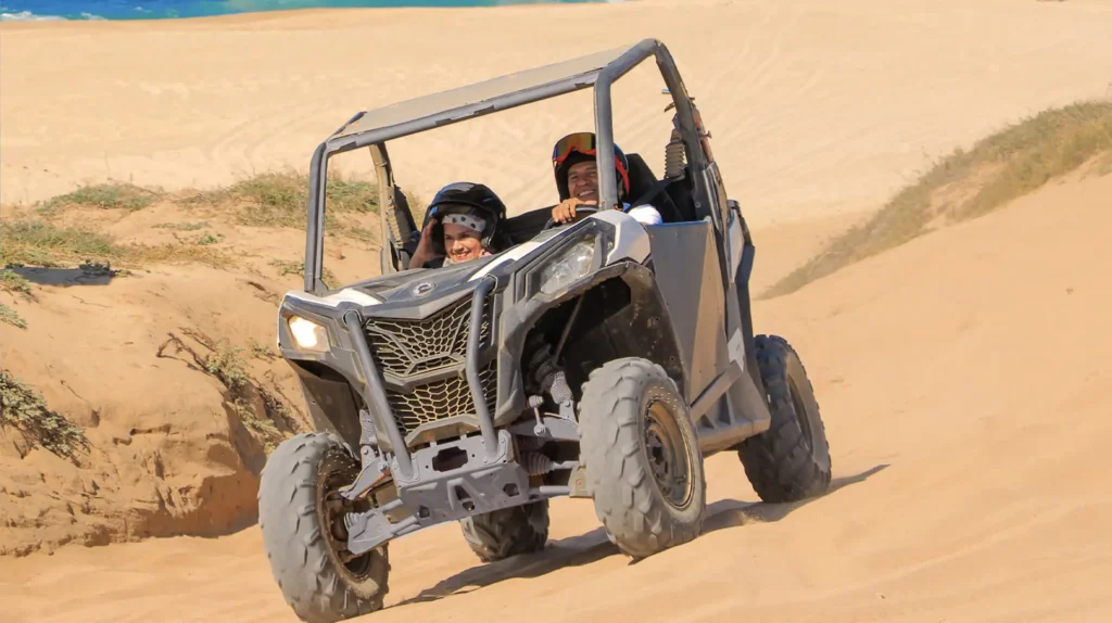 Couple enjoying a Side by Side UTV ride on sand dunes in Los Cabos