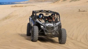 Can-Am Maverick X3 driving across sand dunes during off road tour by the ocean in Los Cabos