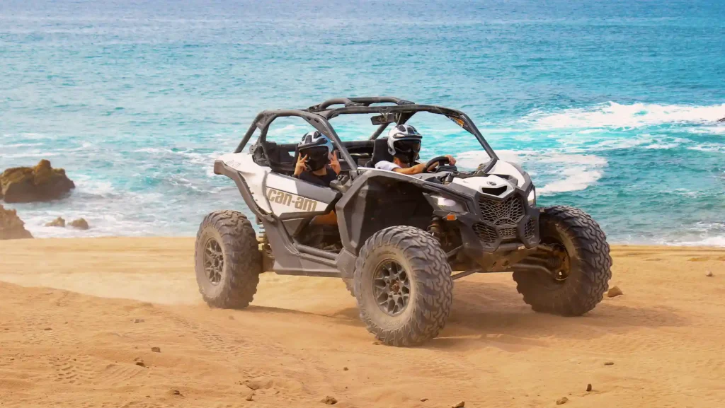 ALT English: Can-Am Maverick X3 riding along the beach in Los Cabos with the ocean in the background during off road tour